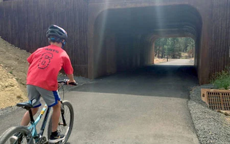 boy riding bike on a bike path through a tunnel